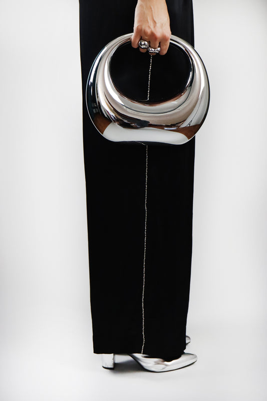 Bolsa plateada de aro mujer sosteniendola pantalón negro